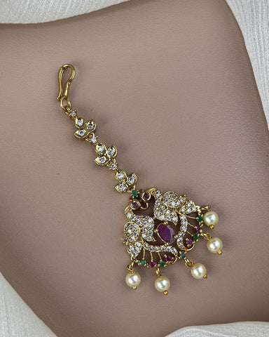 Decorative gold bracelet with pearls and gemstones on a person's wrist.