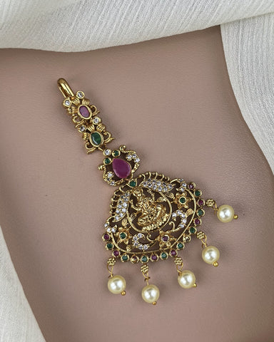 Decorative gold belly button ring with pearls and gemstones on a neutral background