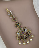 Decorative gold necklace with pearls and gemstones on a neutral background