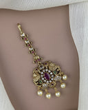Decorative gold pendant with pearls and gemstones on a plain background