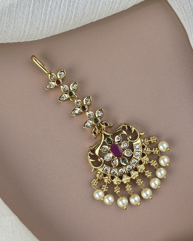 Gold necklace with pearls and red gemstones on a neutral background