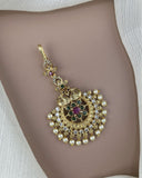 Decorative gold pendant with pearls and gemstones on a plain background