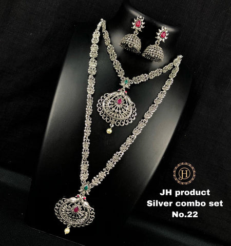 A silver oxidized jewelry set displayed on a mannequin, including a long necklace, a short haram necklace, and two earrings with intricate designs and colorful stones.